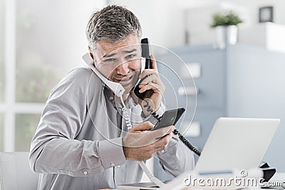 Stressed businessman having multiple calls Stock Photo