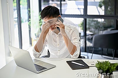 Stressed businessman talking on the phone with his worker and fixing the problems over the phone Stock Photo