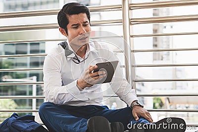 Stressed businessman worry financial bankruptcy. Depressed asian male sitting on the street tired after failed to rescue company Stock Photo