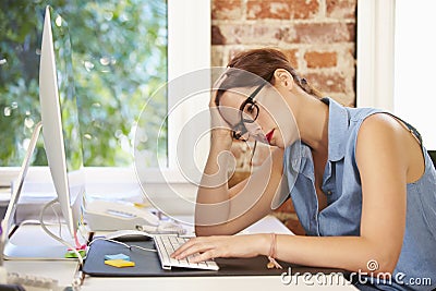 Stressed Businesswoman Working At Computer In Modern Office Stock Photo