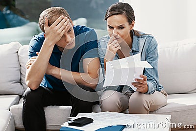 Stressed couple looking frustrated, having no money to pay off their debts, managing family budget together Stock Photo