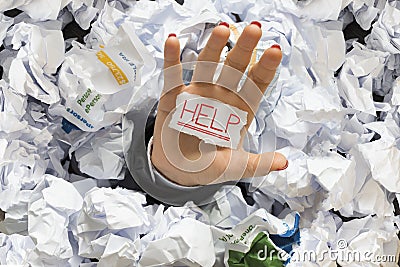 Stressed employee covered with wastepaper at work, asking for help Stock Photo