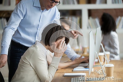 Stressed female employee suffering from discrimination of angry male boss Stock Photo