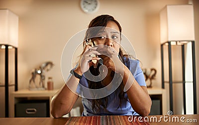 Stressed filipina nurse taking phonecall at home Stock Photo