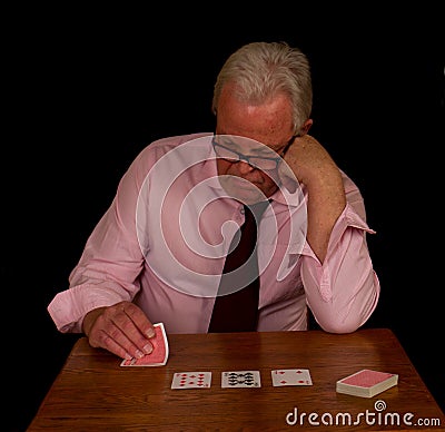Stressed looking elderly man playing poker Stock Photo