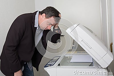 Stressed man in front of a copy machine Stock Photo