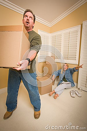 Stressed Man Moving Boxes for Demanding Wife Stock Photo