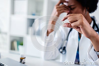 Stressed medical worker working at her office taking pill Stock Photo
