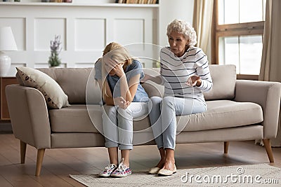 Stressed millennial blonde woman ignoring angry senior old mother. Stock Photo