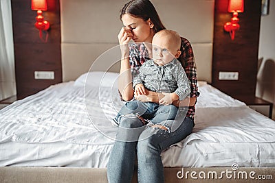 Stressed mother with little child sitting on bed Stock Photo