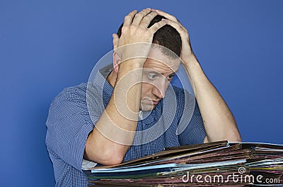 Stressed out man at work in front of a pile of files. Stock Photo