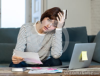 Stressed and overwhelmed young woman paying credit card debts and bills on laptop Stock Photo