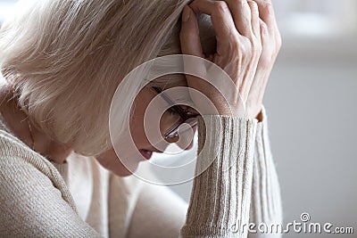 Sad tired senior woman holding head in hands feeling headache Stock Photo