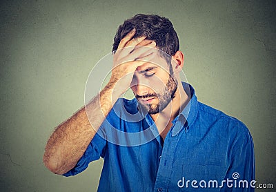 Stressed sad young man looking down on gray wall background Stock Photo
