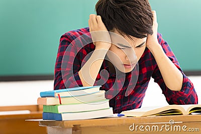 Stressed student studying for exam in classroom Stock Photo