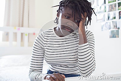 Stressed Teenage Girl Sitting In Bedroom At Home Stock Photo