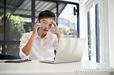 Stressed Asian businessman dealing business with his business client over the phone Stock Photo