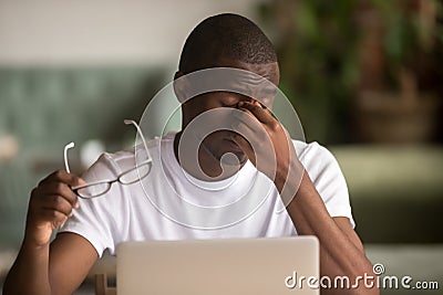 Stressed tired from computer work african man feeling eye strain Stock Photo