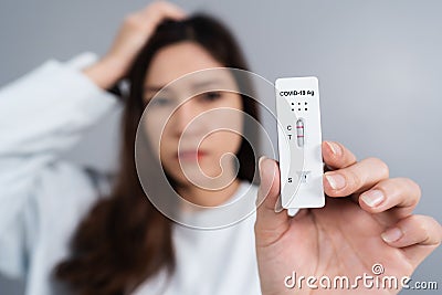 Stressed woman holding CoronavirusCovid-19 positive test result with Antigen Rapid Test kit ATK Stock Photo