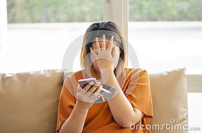 Stressed woman holding her face, scammer stealing money from online transaction, holding credit card and mobile phone Stock Photo