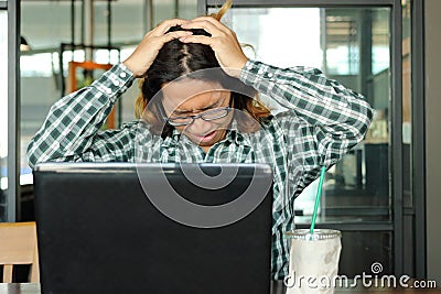 Stressed young Asian business man with hands on head feeling tired against his work in office. Exhausted and overwork job concept. Stock Photo