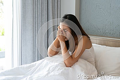 Stressed young Asian woman suffering on depression and sitting alone in bedroom at home. sad, unhappy, disappointed concept Stock Photo