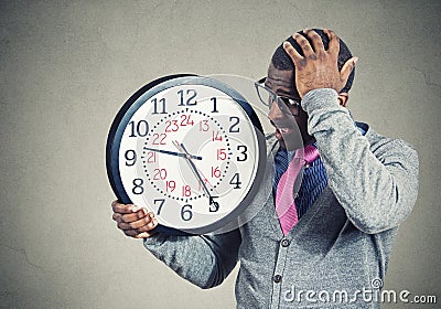 Stressed young man running out of time looking at wall clock Stock Photo