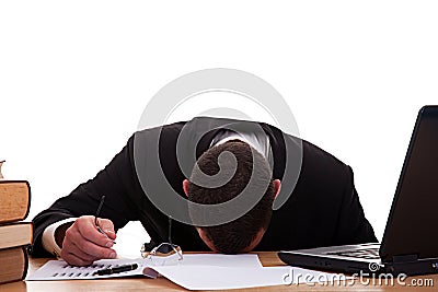 Stressed young man sitting at a table among books Stock Photo