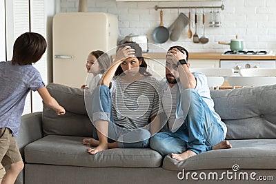 Stressed young parents tired of crazy loud children. Stock Photo