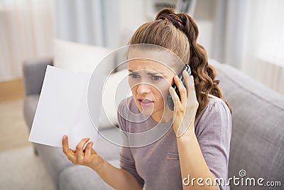 Stressed young woman holding letter and talking cell phone Stock Photo