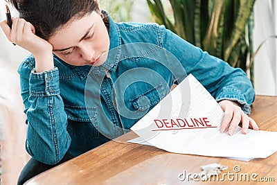 Stressed young woman is sitting at a table with documents, money and keys. The concept of mortgage debt and deadline Stock Photo