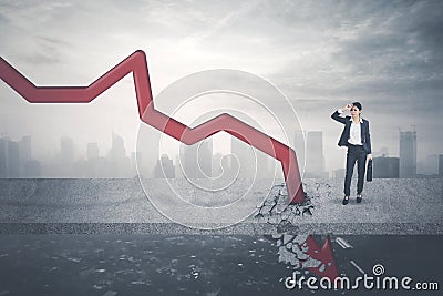 Stressful businessman looking at a declining arrow Stock Photo