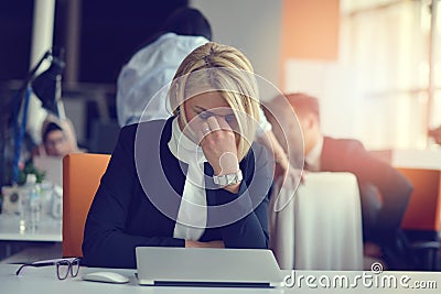 Feeling tired and stressed. Frustrated adult woman keeping eyes closed from fatigue while sitting in office. Stock Photo