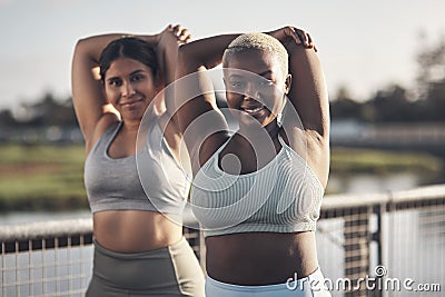 Stretch, your body will thank you later. two young women stretching while outside for a workout. Stock Photo
