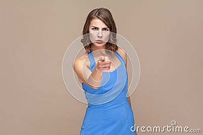 Strict bossy woman with wavy hair pointing at you, looking at camera with serious expression. Stock Photo