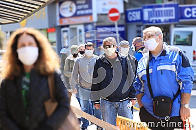 With strict control and disinfection people, wearing face masks for prevention of coronavirus COVID-19 disease, in a line for Editorial Stock Photo