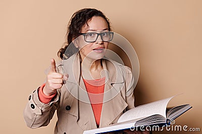 Strict female teacher with glasses, points her index finger at camera, warning you about the importance of reading books Stock Photo