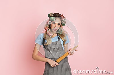 Strict housewife in apron with spots of flour and rolling pin in hands Stock Photo