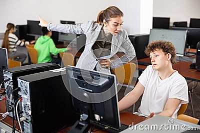 Strict teacher reprimanding negligent teenage student in computer class Stock Photo