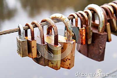 A string of many keys attached to a metal rope with a brown river water background Stock Photo