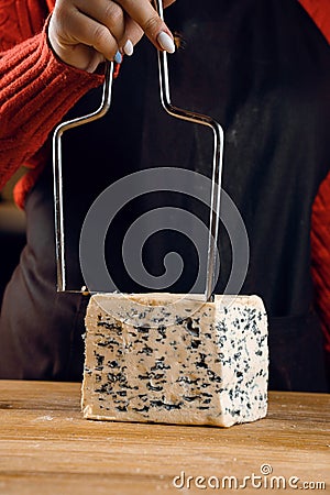 String for slicing blue cheese. Mix of cheeses on plate. Slicing dorblu, gorgonzola, roquefort. French gourmet cuisine. Stock Photo