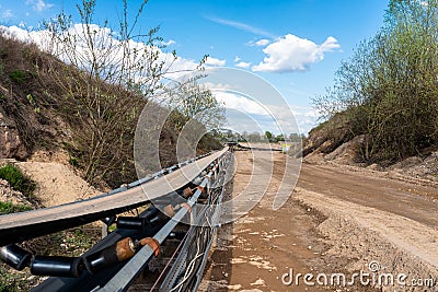 A string of transport belting in a gravel pit for transporting gravel and sand over long distances, belts go along the road. Stock Photo