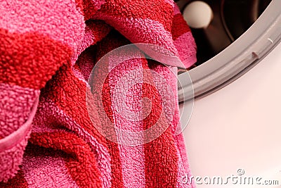 A striped bath towel lies on the brim of a washing machine drum Stock Photo