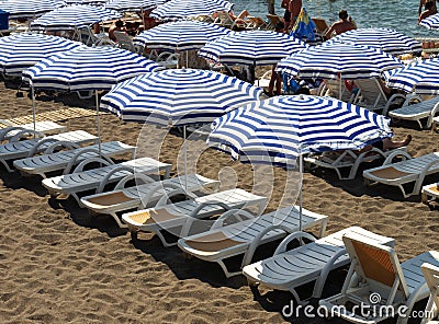 Striped beach umbrellas and white sunbeds Editorial Stock Photo