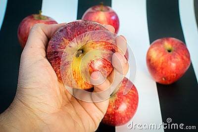 Striped black and white background. Hand holding and apple and red apples on striped black and white background, as a Stock Photo