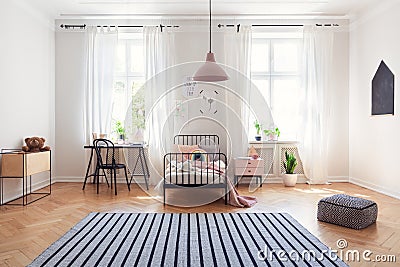 Striped carpet and pink lamp in teenager room interior with bed next to desk and chair Stock Photo