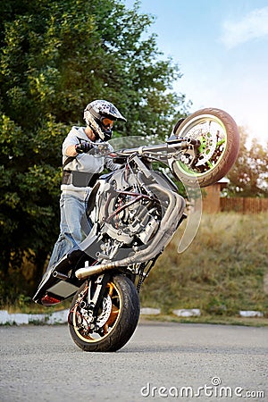 Strong biker showing extreme stunt on one wheel. Editorial Stock Photo
