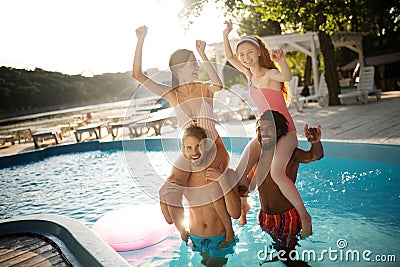 Strong boyfriends holding their girlfriends while chilling in pool Stock Photo