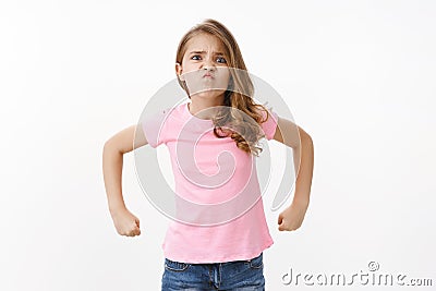 Strong brave cute little girl child acting mature and strong, showing power and ability stand for herself, pouting Stock Photo