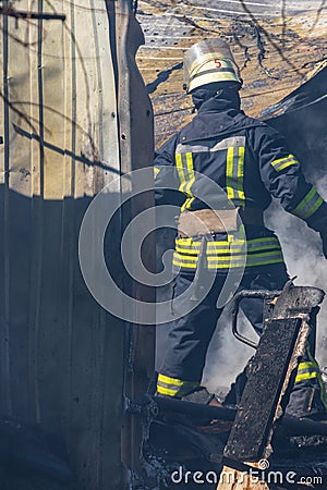 A strong and brave fireman rescues a burning building using water in a fire operation. Fireman in a fire protection suit. Stock Photo